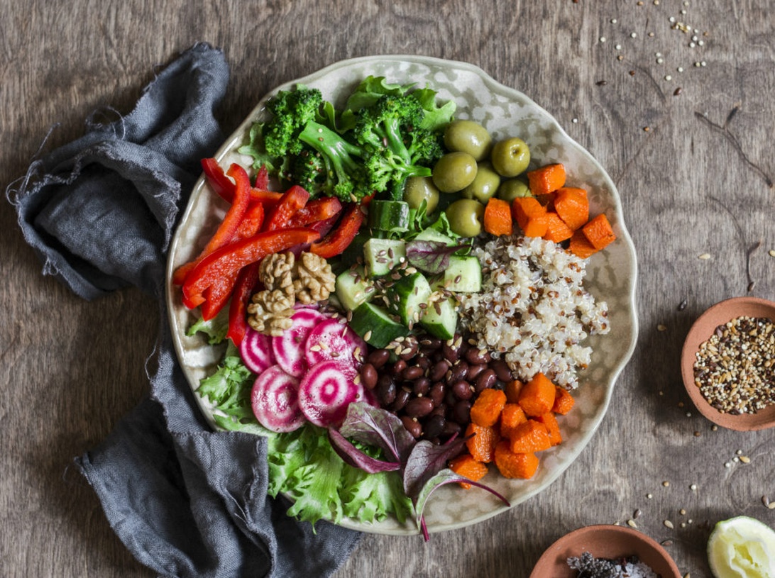 En vackert arrangerad vegansk buddha bowl med quinoa, broccoli, paprika och andra färgglada grönsaker.